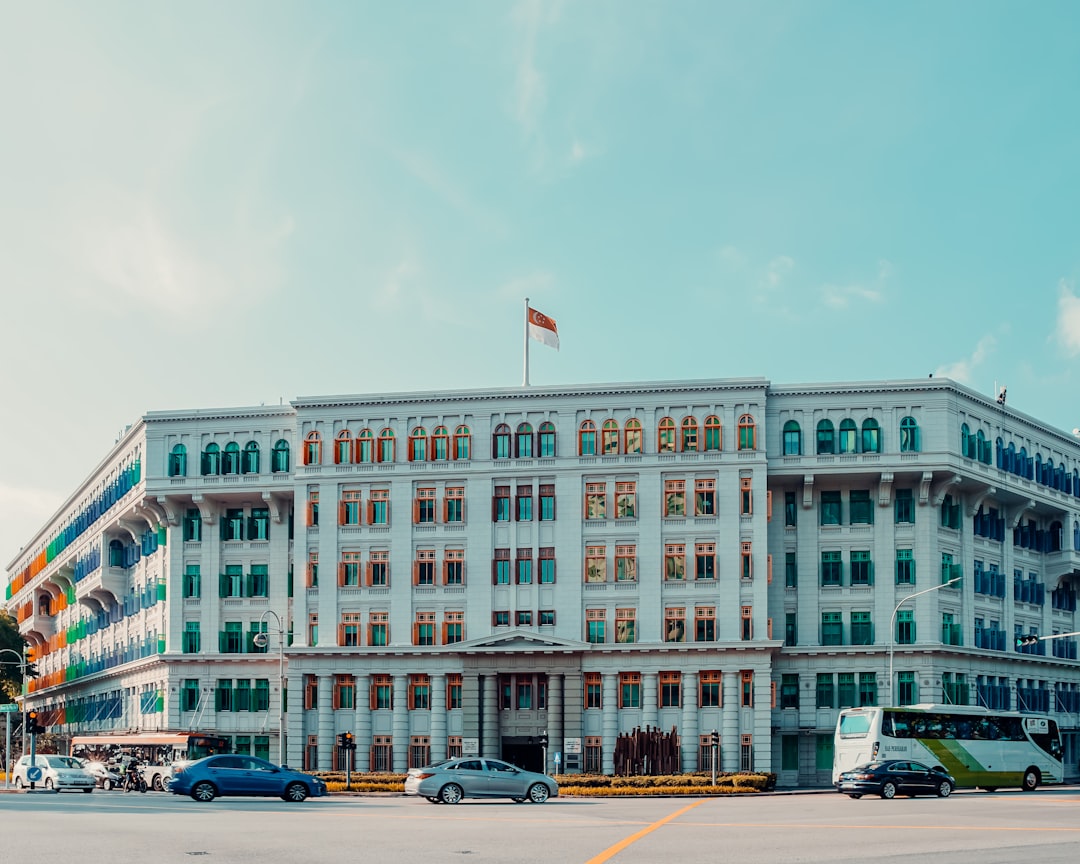Historic colonial building with Singapore flag flying atop turquoise facade and arched windows