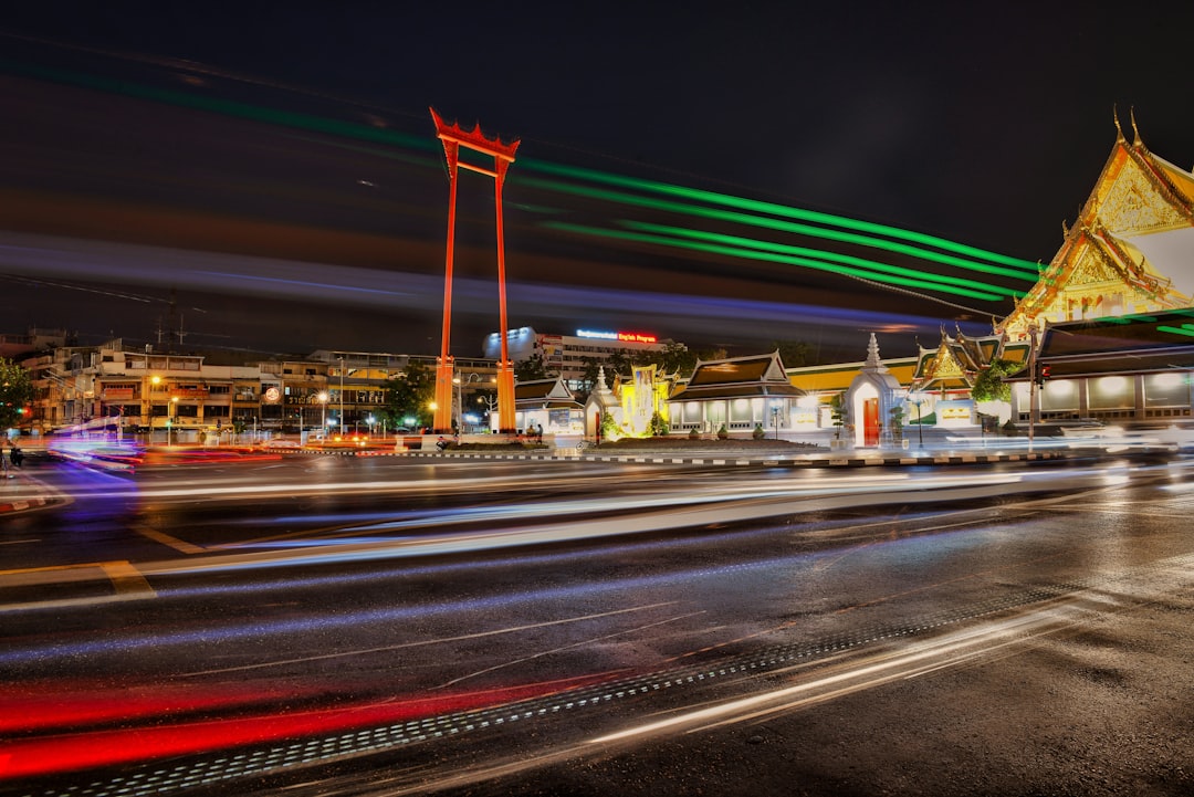 Night scene of Bangkok's Giant Swing with illuminated Thai temple and light trails from traffic