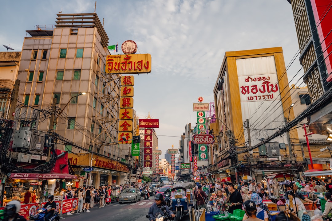 Busy street in Bangkok's Chinatown with colorful Thai and Chinese signs, crowded shops and pedestrians